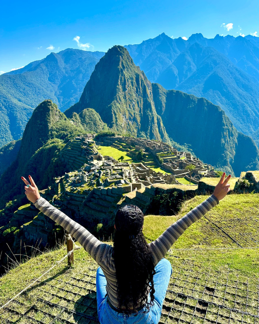 Machu-Picchu-17 Mulher de costas sentada, com vista panorâmica de Machu Picchu ao fundo